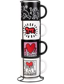 Комплект чаши Grupo Erik - Keith Haring, 4 бр.: керамични чаши с черни дръжки на метална стойка, украсени със стилизирани фигури, куче и сърца в стил Keith Haring в черно, червено и бяло.