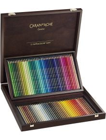 В отворена тъмна дървена кутия е изложен Caran d'Ache Supracolor Комплект цветни моливи с 80 ярки нюанса в две тавички. На капака е изписано Caran d'Ache Genève 80 Supracolor Soft, идеален за всяка колекция книжарница Orange.
