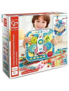 Малко дете се усмихва, докато държи в ръка шарен "Комплект за игра Hape - Експерименти с колела". Кутията показва 115 образователни играчки, предназначена е за възраст 3+ и съдържа STEAM икони.