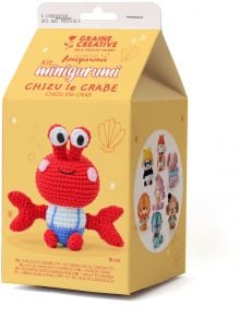 Жълта кутия Комплект за плетене Амигуруми Graine Creative - Рак Чизу за изработване на червено плетено раче на име Чизу. В кутията са показани илюстрации на морски обитатели и снимки на други плетени на една кука фигурки на животни.