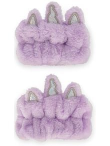 Две пухкави, светлолилави ленти за китки Legami - Unicorn с три меки елемента като уши и рог на еднорог, декорирани със сребриста материя-идеални за рутинна грижа за кожата, на бял фон.