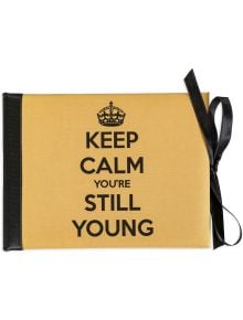 Луксозна картичка за рожден ден - Keep calm you're still young (Запази спокойствие, все още си млад) има жълта корица, черен гръб и панделка, смел черен текст "KEEP CALM YOU'RE STILL YOUNG" и символ на корона - идеален за рождени дни.
