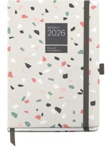 Останете организирани през 2026 г. Със Седмичен тефтер - органайзер Miquelrius Grafica Terrazo 2026 с терацо корица, ластик за затваряне, държач за химикал и надпис WEEKLY 2026 отпред.