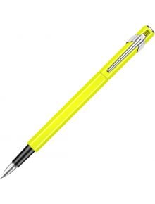 Писалка Caran d'Ache 849 Metal Fluo Yellow със сребърен клипс и черна част на дръжката, разположена диагонално на бял фон. Предлага се в книжарница Orange.
