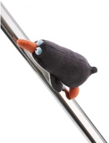 Плюшен магнит Nici - Пингвинът Хорхе е с оранжеви клюн и крачета, вкопчен за метална тръба под ъгъл, сякаш се пързаля. Идеален за хладилник и забавен подарък, върху изчистен бял фон.