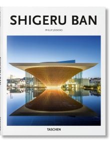 Корицата на книгата "Шигеру Бан" от Филип Джодидио, на която е показана модерна сграда с извит дървен покрив - символ на хуманитарния дизайн на Бан - огледана във вода под ясно небе. Издател: ИЗДАТЕЛСТВО: TASCHEN.