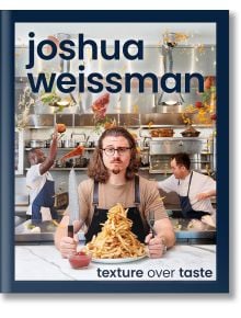 Мъж с очила и дълга коса седи на маса, държи прибори и се взира във висока купчина пържени картофи. Готвачи работят в оживената кухня зад него. Текст: Джошуа Вайсман: Вдъхновен от неговата готварска книга.